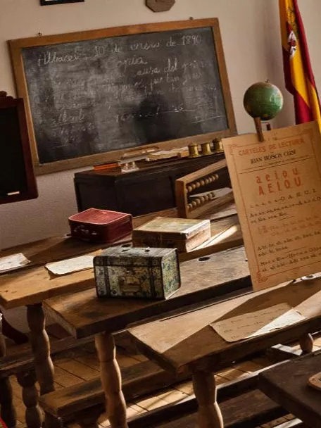 Detalle de pupitre antiguo con pizarra individual y cuadernos escolares.
