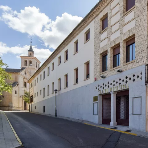 Calle con teatro municipal y torre de iglesia al fondo