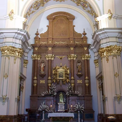 Detalle del altar principal con columnas, dorados y esculturas religiosas.