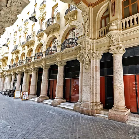 Soportales con columnas de piedra y fachadas clásicas a lo largo de una calle cubierta.