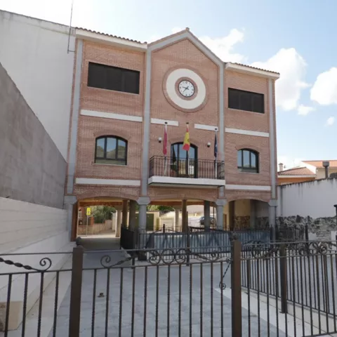 Edificio municipal de ladrillo con reloj y banderas