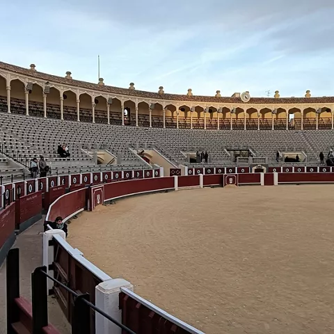 Vista lateral del graderío con arena y personas dispersas.