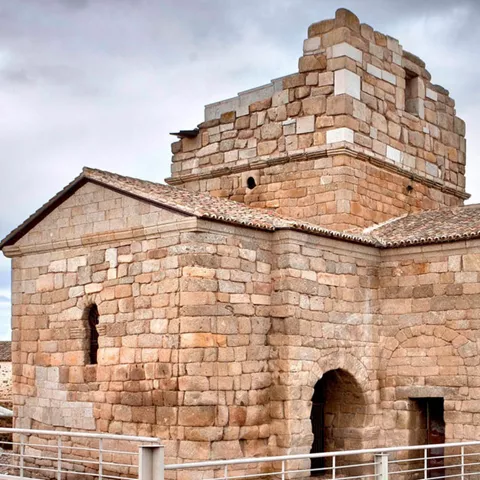 Edificio religioso de piedra con ábsides y cubierta de teja.