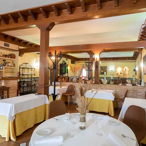 Salón rústico con vigas de madera y mesas vestidas