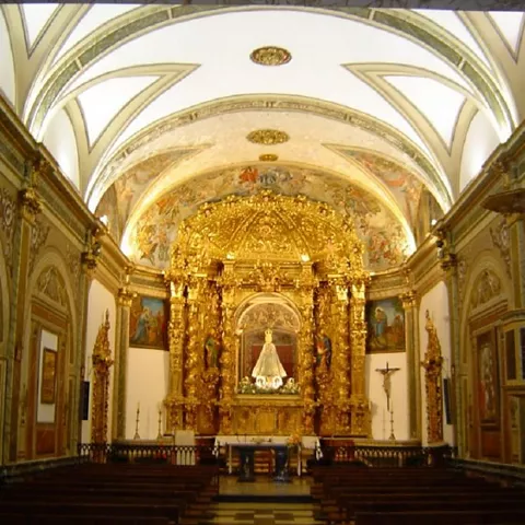 Nave central con retablo dorado y altar iluminado.