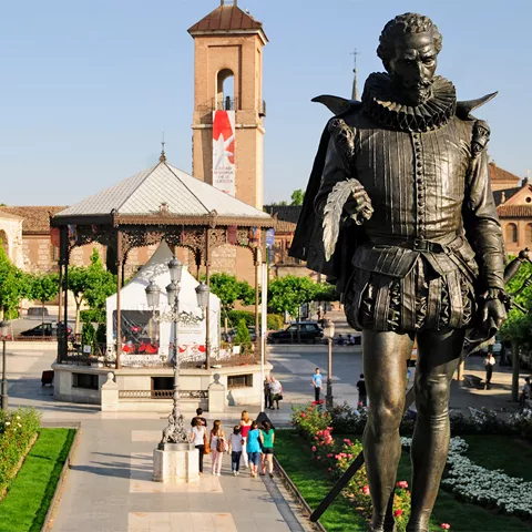 Estatua de escritor clásico en plaza histórica con jardín