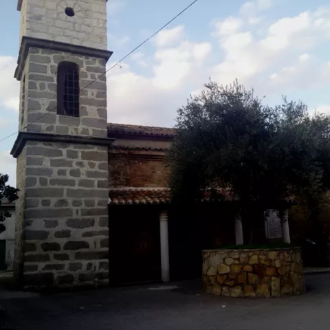 Edificio religioso de piedra con torre y árbol en primer plano