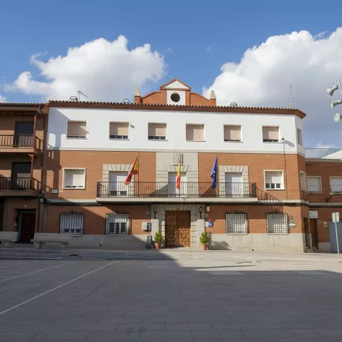 Fachada de edificio municipal con balcón y banderas