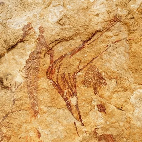 Detalle de pintura rupestre de animal en tonos rojizos sobre roca clara.