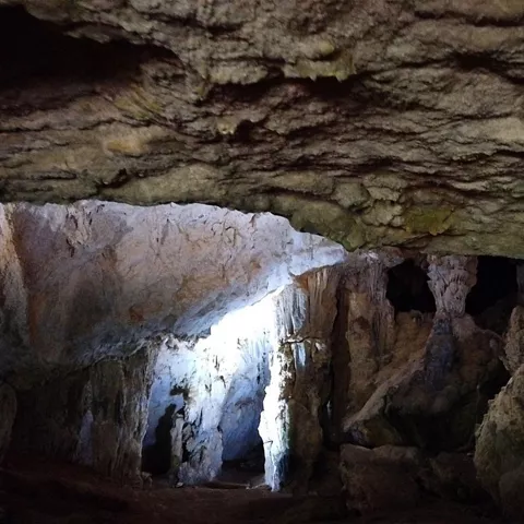 Interior de cueva con formaciones rocosas iluminadas por una abertura natural.