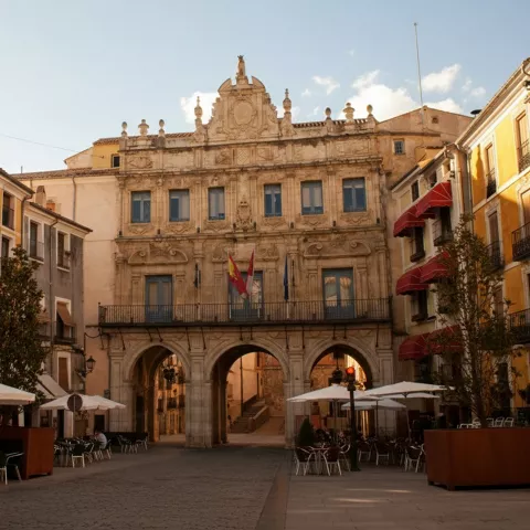 Plaza con terrazas frente a edificio porticado