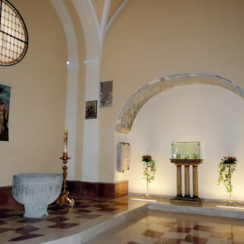Capilla interior con pila bautismal y vitrales.