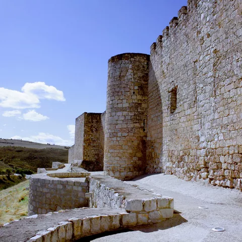 Camino junto a murallas y torre defensiva.