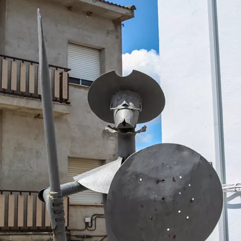 Escultura metálica con lanza y escudo en entorno urbano
