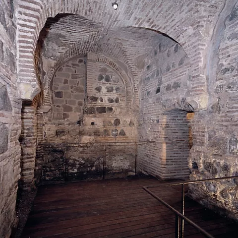 Sala abovedada de ladrillo y piedra con suelo de madera.