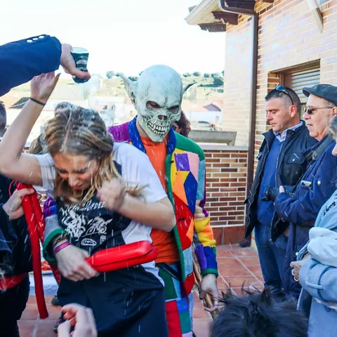 Persona con máscara vierte agua durante la celebración.