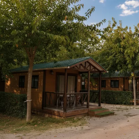 Piscina vallada con césped, árboles alineados y agua al fondo entre colinas.
