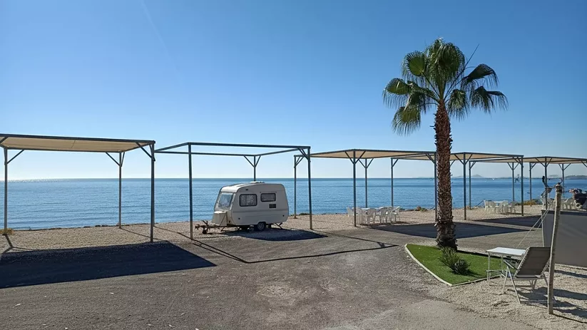 Parcela de camping frente al mar con caravana y palmera