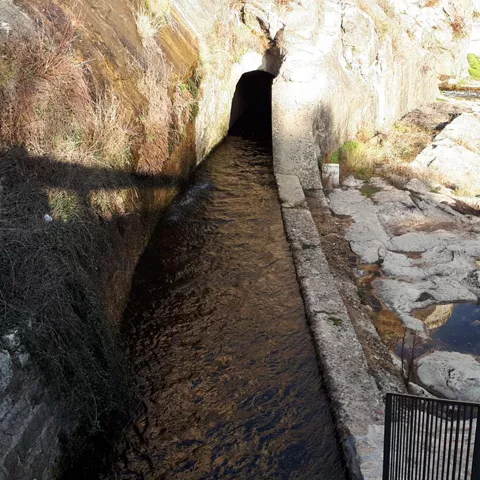 Canal de agua bajo un paso excavado en roca.
