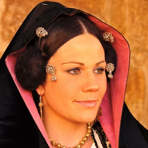 Retrato de mujer con mantilla negra, joyas doradas y peinado tradicional.