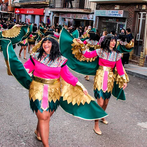 Desfile de comparsa con trajes verdes y dorados en la calle