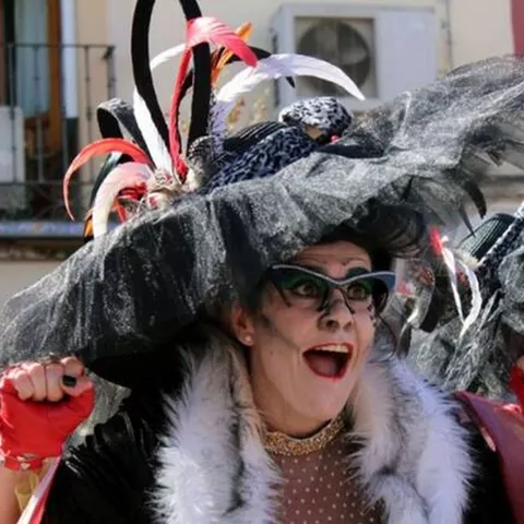 Grupo disfrazado con sombreros negros grandes, gafas llamativas y guantes rojos en la calle.