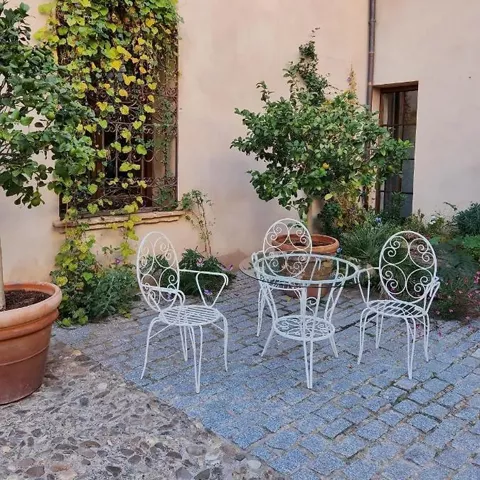 Rincón de patio con mesa de forja y plantas