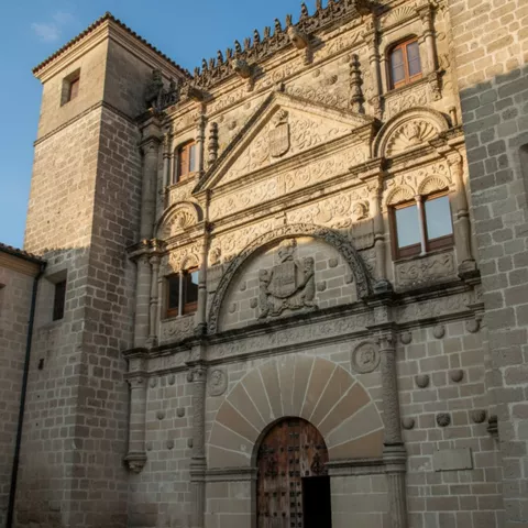 Detalle de portada de piedra tallada con escudo sobre puerta de madera