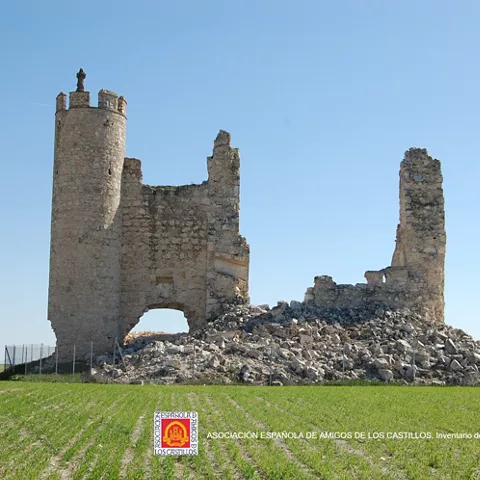 Torre y muros derruidos junto a campo cultivado
