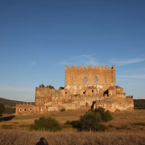 Fachada frontal de una fortaleza en lo alto de una loma, con cielo despejado.