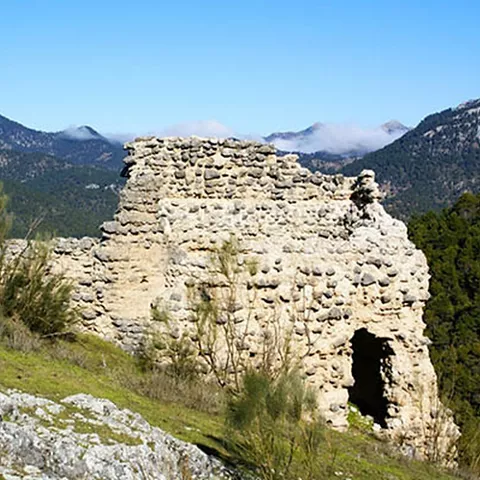 Estructura defensiva derruida con montañas al fondo.