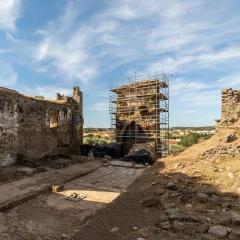 Interior de fortaleza antigua con muros de piedra y torre central rodeada de andamios.