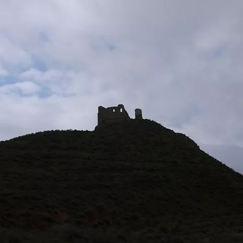 Silueta de fortificación en lo alto de una colina al anochecer.