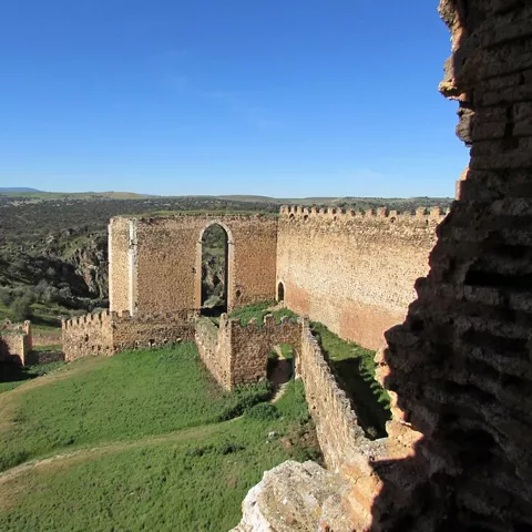 Interior de fortaleza con muros de piedra y vistas al paisaje