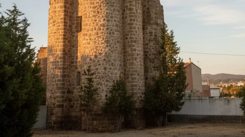 Torre circular de piedra iluminada por el atardecer.