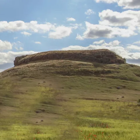 Cerro cubierto de vegetación bajo cielo nuboso.