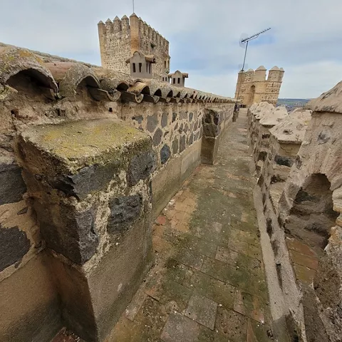 Paso de ronda sobre la muralla con almenas y torres defensivas.