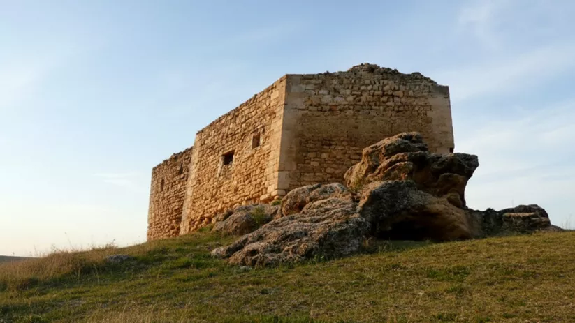 Restos de castillo en cresta rocosa con valle al fondo.