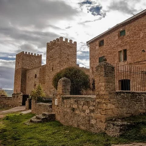 Conjunto fortificado junto a edificio de piedra y verja.