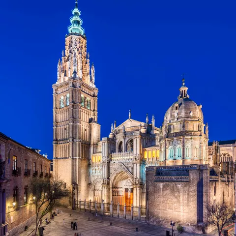 Gran templo iluminado al anochecer con torre y cúpula.