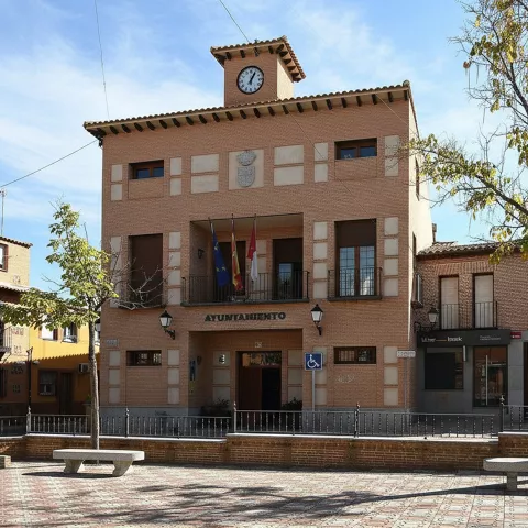 Edificio municipal en plaza con bancos y arbolado