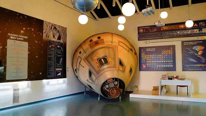 Interior de un centro astronómico con una cápsula espacial en exposición.