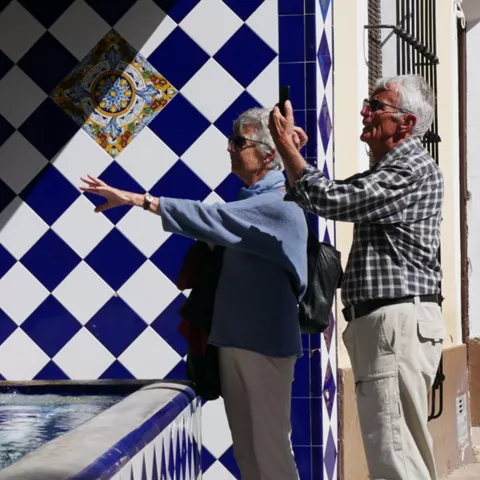 Pareja de personas mayores observando una fuente de azulejos azules.