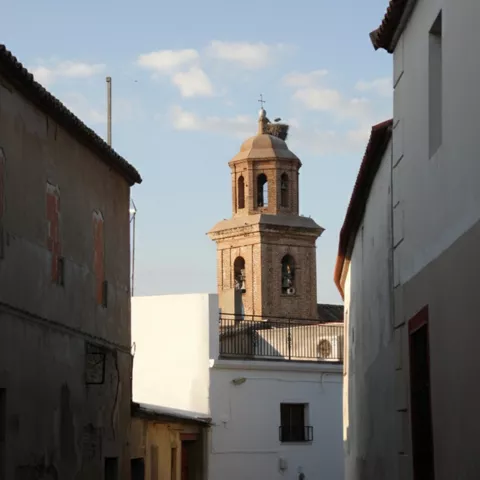 Calle estrecha con torre de iglesia al fondo