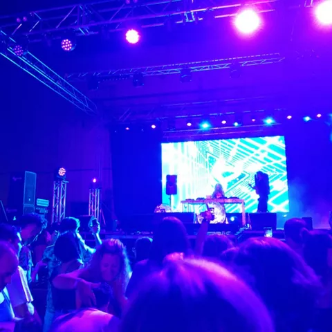 Público frente a cabina de DJ con luces violetas