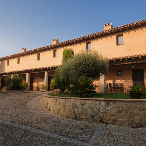Fachada de alojamiento rural con camino empedrado y jardín al anochecer.