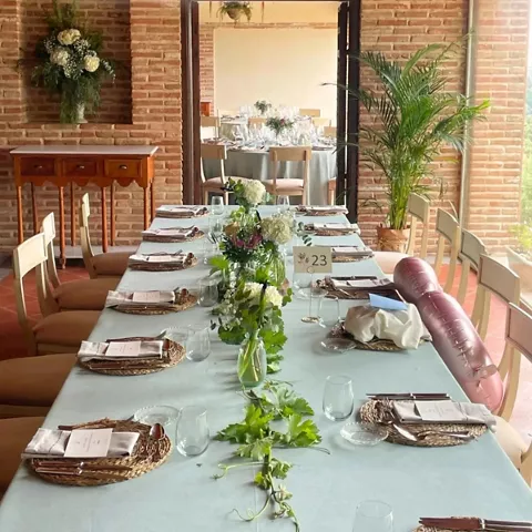 Mesa alargada decorada para celebración en salón con paredes de ladrillo
