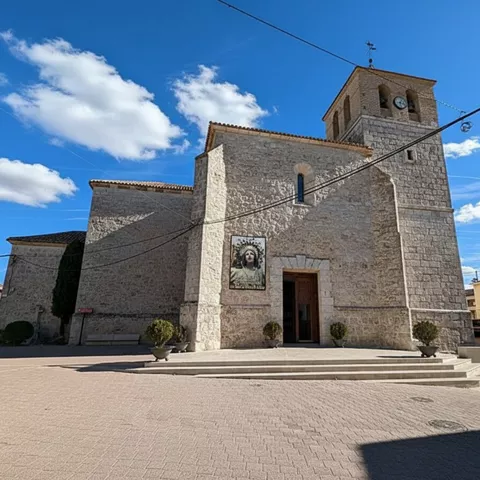 Iglesia de piedra con torre y plaza despejada