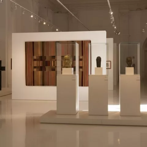 Busto escultórico en pedestal dentro de galería contemporánea.