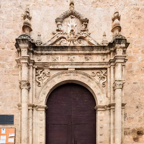 Puerta de madera en portada barroca de piedra tallada
